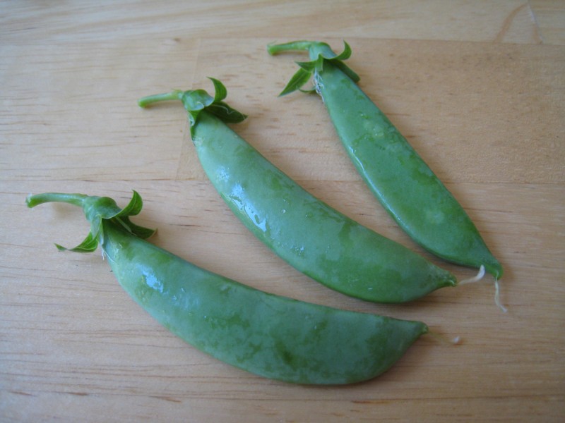 Snap pea pods on cutting board
