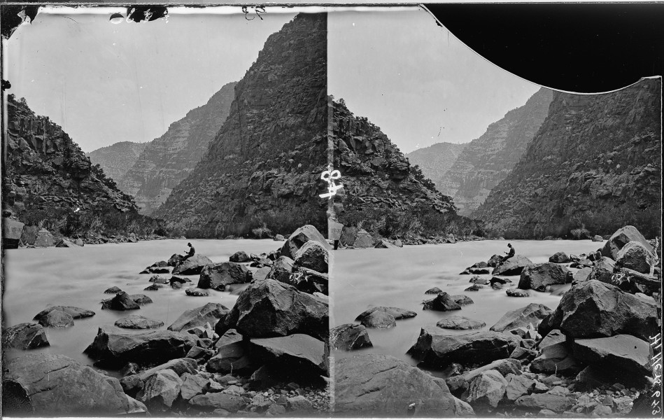 Colorado River. Cataract Canyon, Clem Powell reading while sitting on a boulder in the river. See - NARA - 517890