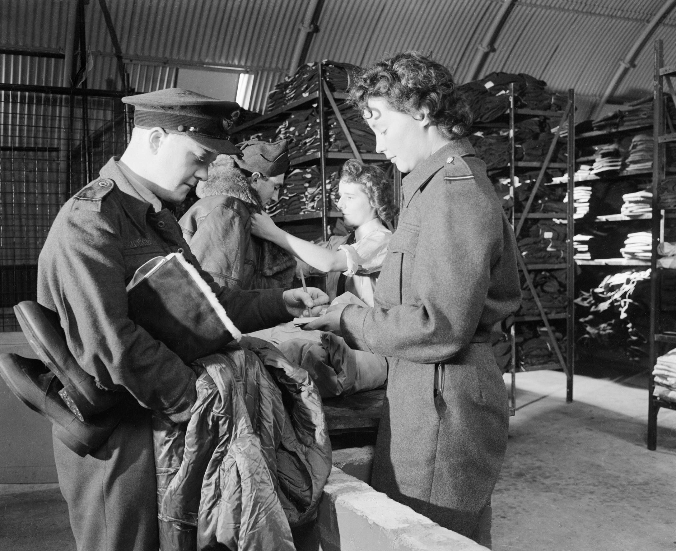 A WAAF section officer and her assistant issue new items of flying kit to aircrew at an RAF bomber station, August 1944. CH13713
