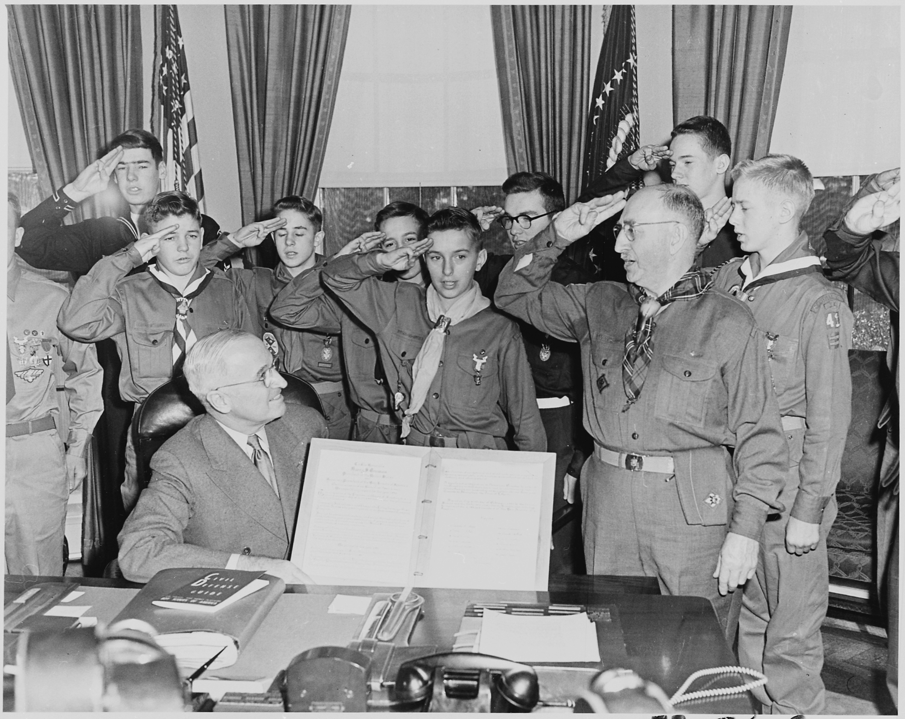 Photograph of President Truman in the Oval Office receiving a report on the accomplishments of the Boy Scouts from a... - NARA - 200293