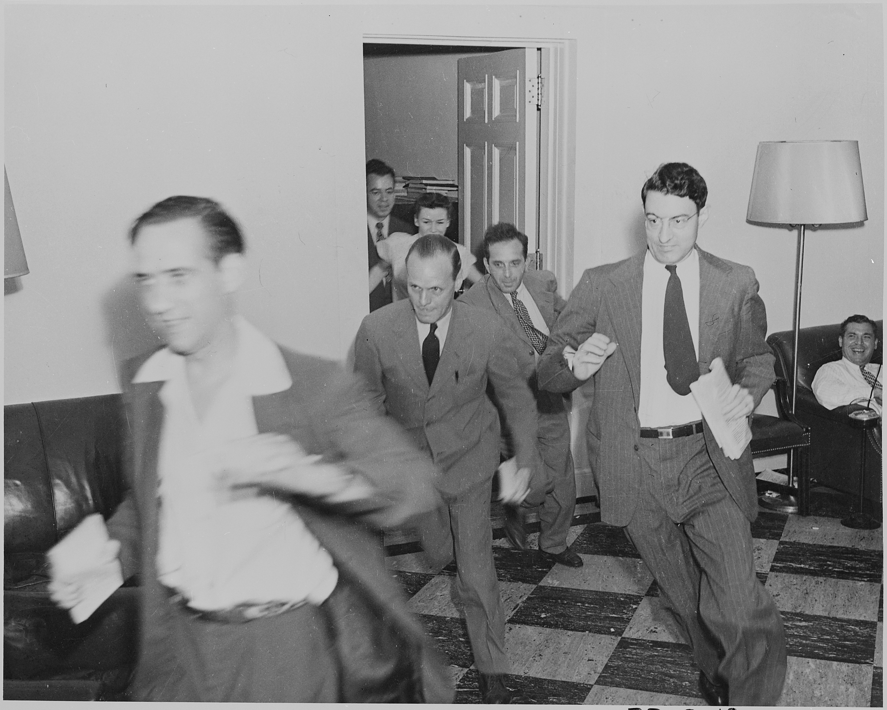 Photograph of reporters rushing excitedly through the White House with news of the Japanese surrender. - NARA - 199172