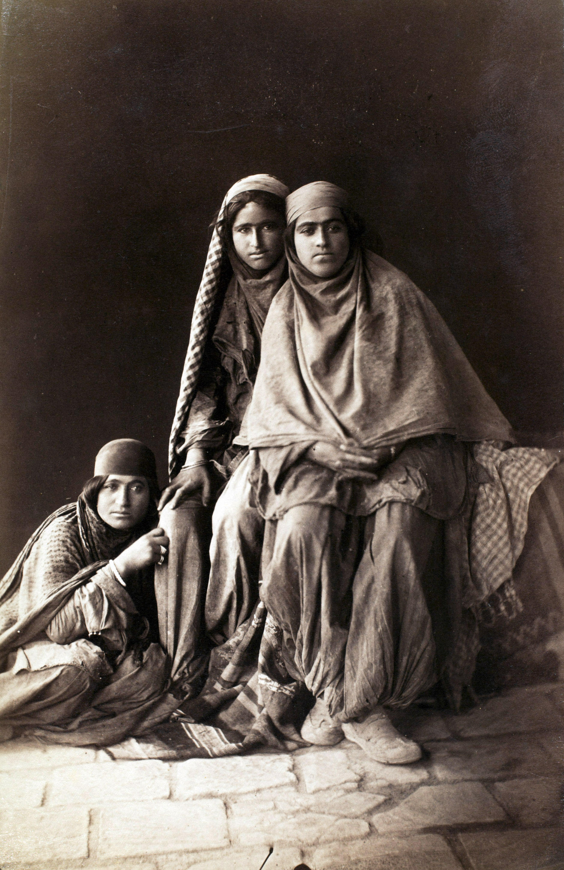 Three women tiredly look at Antoin Sevruguin as he photographs them in the late 19th century.