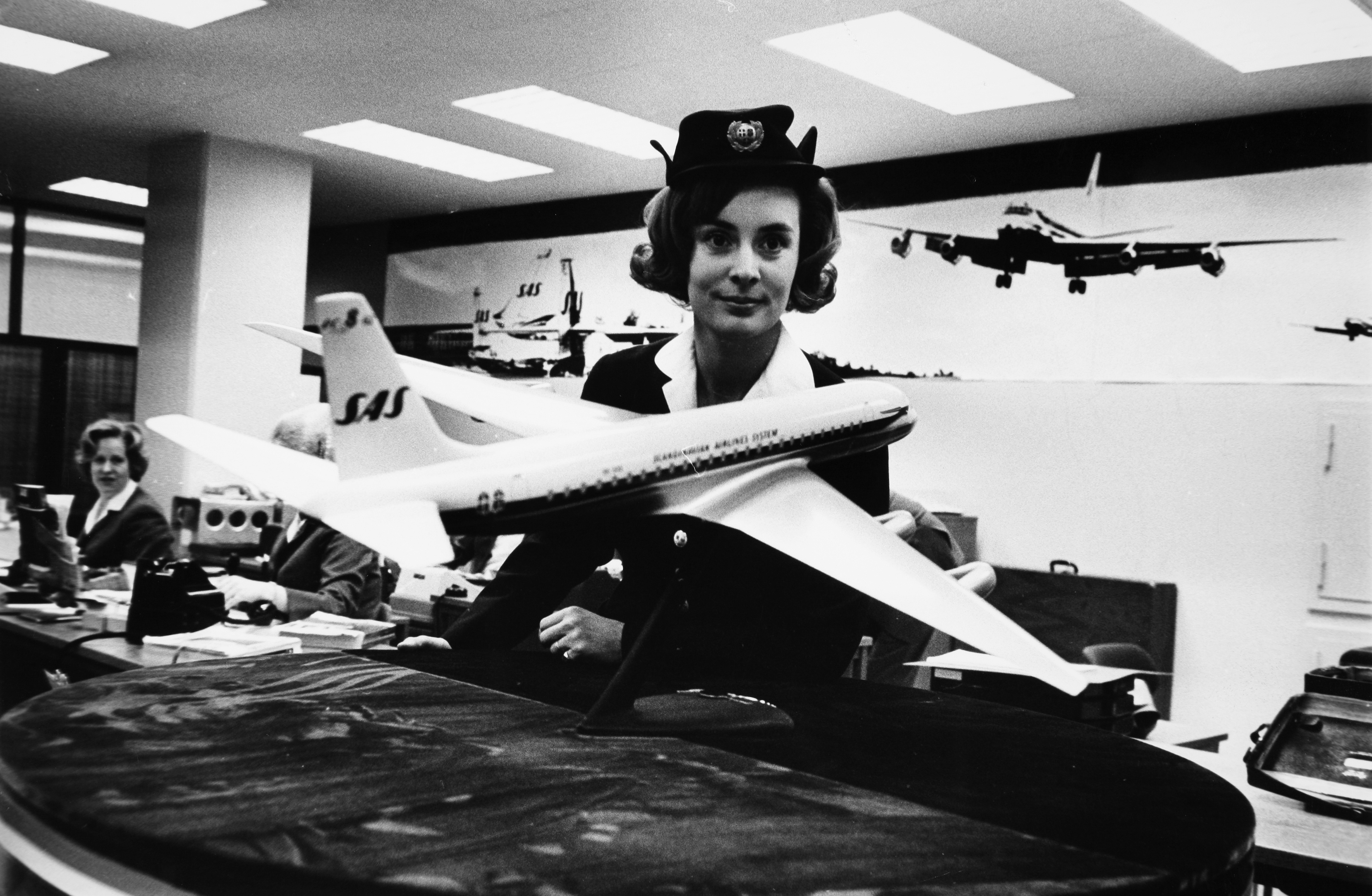 Air hostess poses with a model of the DC-8-62, the new extra-long-range giant SAS put in service in the spring of 1967
