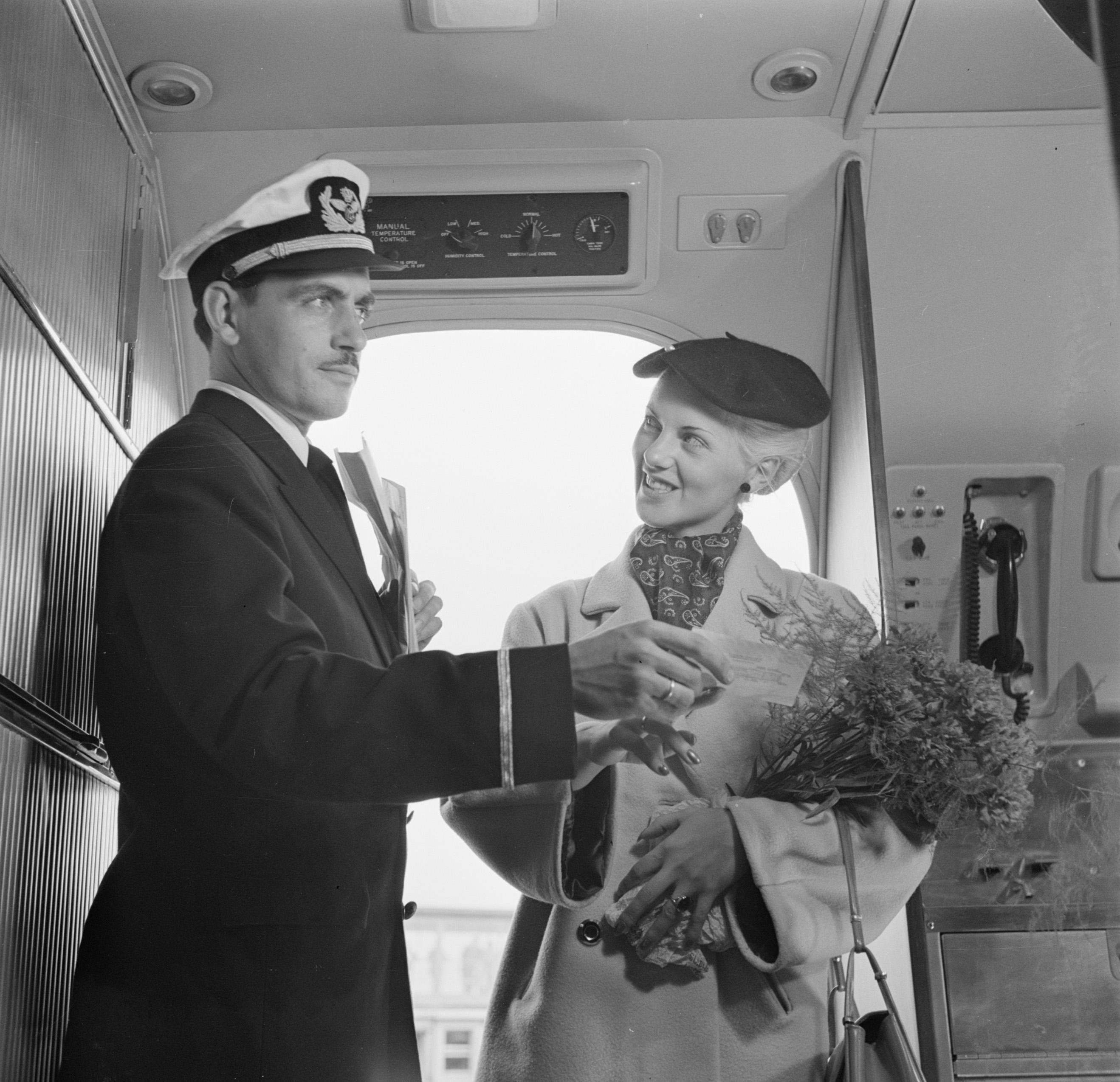 Een KLM-purser verwelkomt een reiziger in de cabine en duidt haar de zitplaats