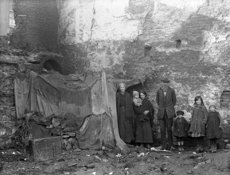 A family pose beside a make-shift shelter Alexander Street, Waterford, Ireland, 1920s (6805869735)