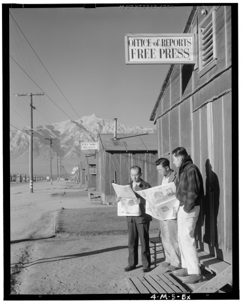 Ansel Adams Manzanar - Roy Takeno (Editor) and group reading Manzanar pap - LOC ppprs-00006