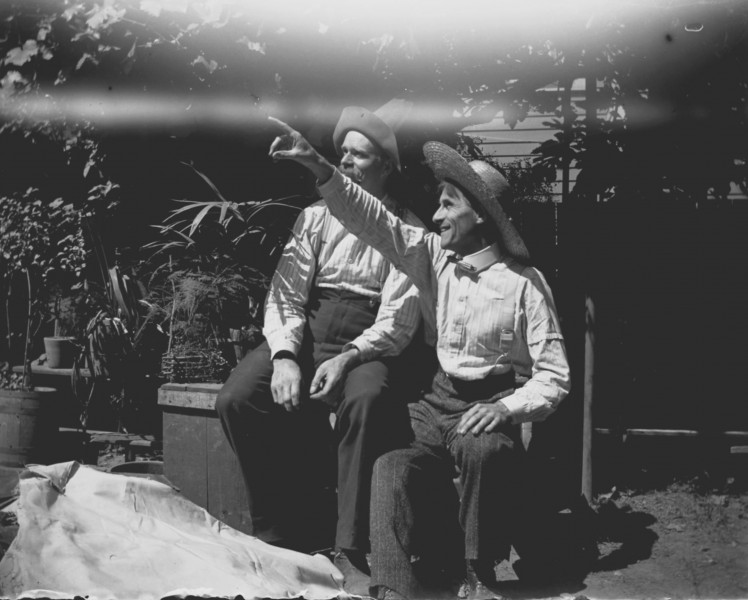 Herman Bohlman and William L. Finley sitting in garden area wearing hats (3945309579)