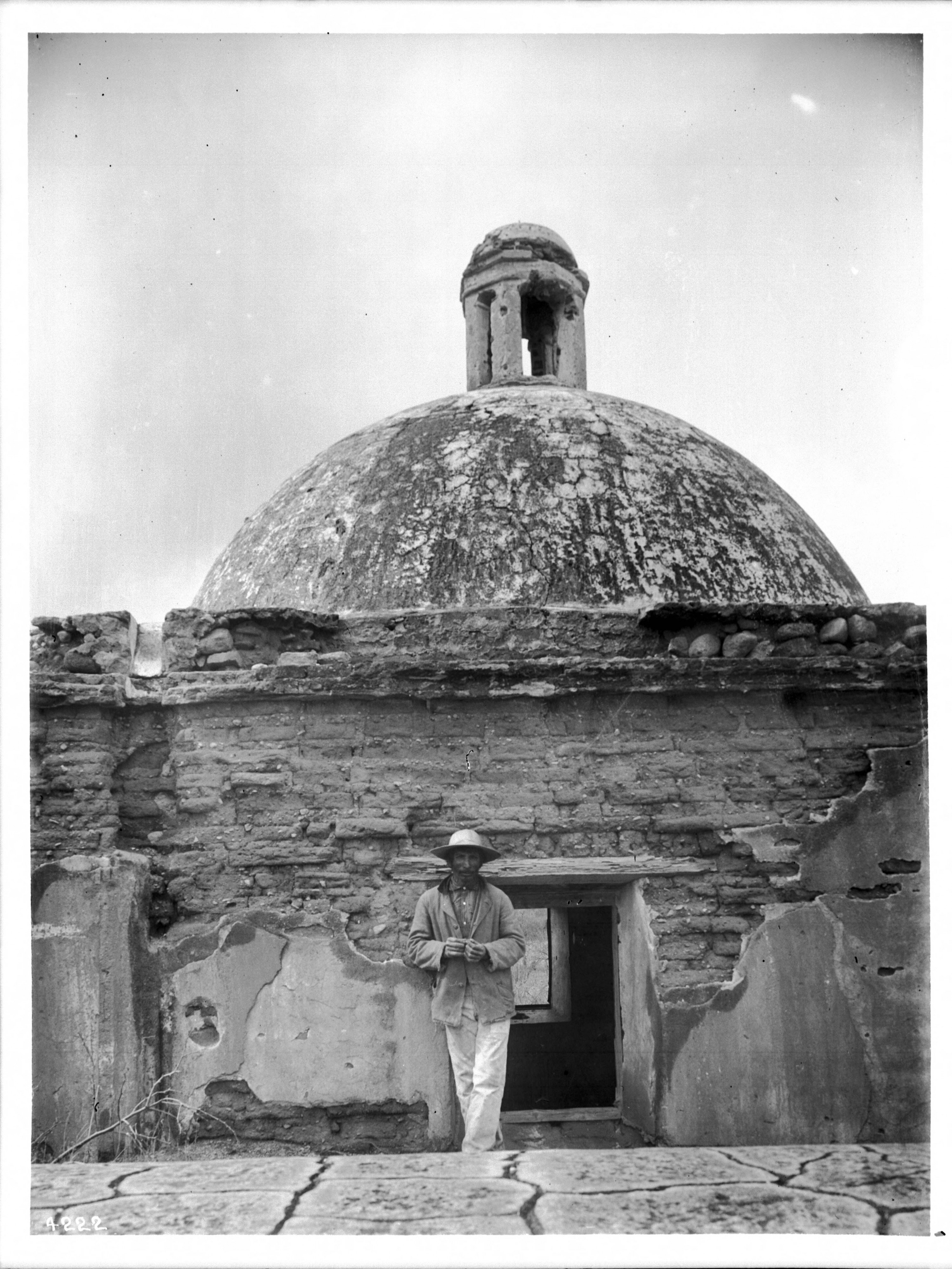 Indian Sacristan standing beside the dome of Mission Tumacacori, Arizona, ca.1908 (CHS-4222)