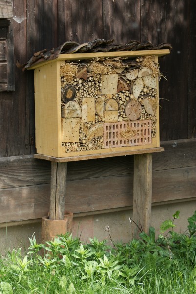 Wildbienenhotel aus Holz und einem Backstein.