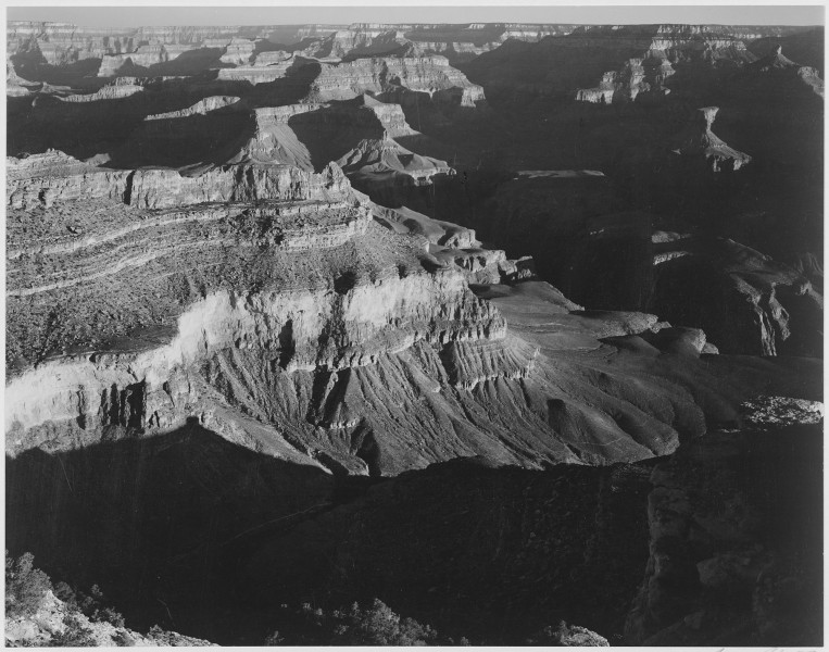 View, dark shadows in foreground and right, framing cliffs at left and center, 