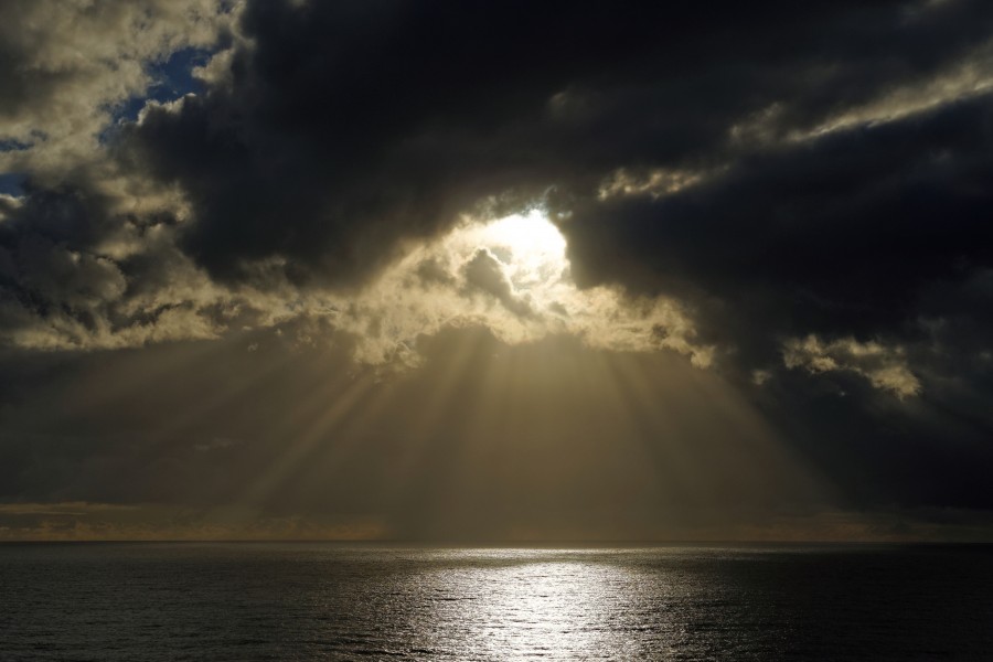 Sun breaking through clouds over ocean