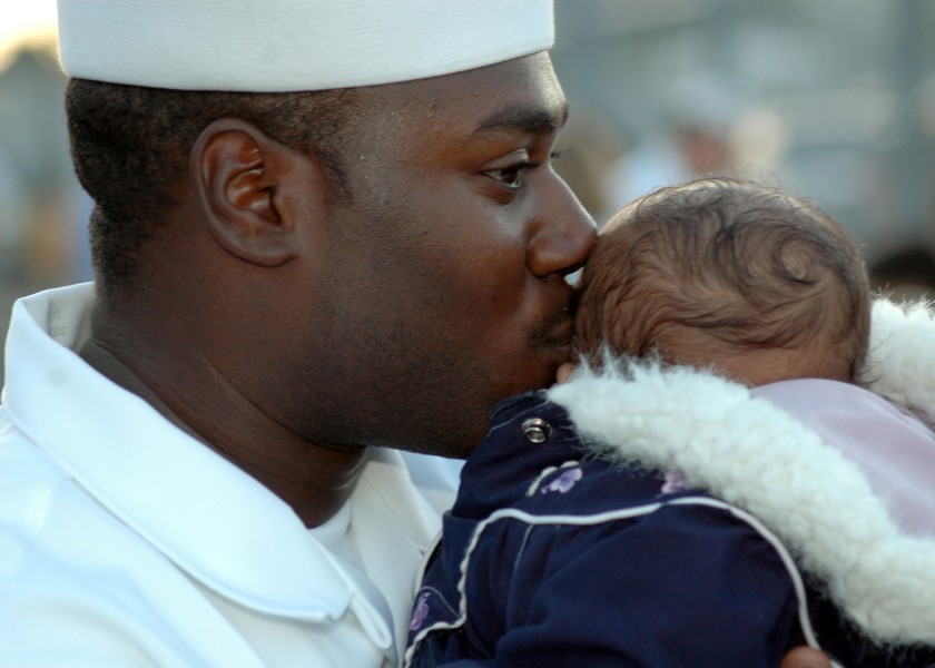 US Navy 060105-N-3019M-002 Boatswain's Mate 3rd Class Leroy Quinn kisses his son on the pier before departing aboard the guided missile destroyer USS Chung-Hoon (DDG 93)