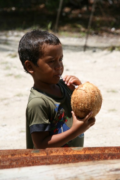 Young boy drinking a coconuts with a straw, in Fakarava atoll 20061106
