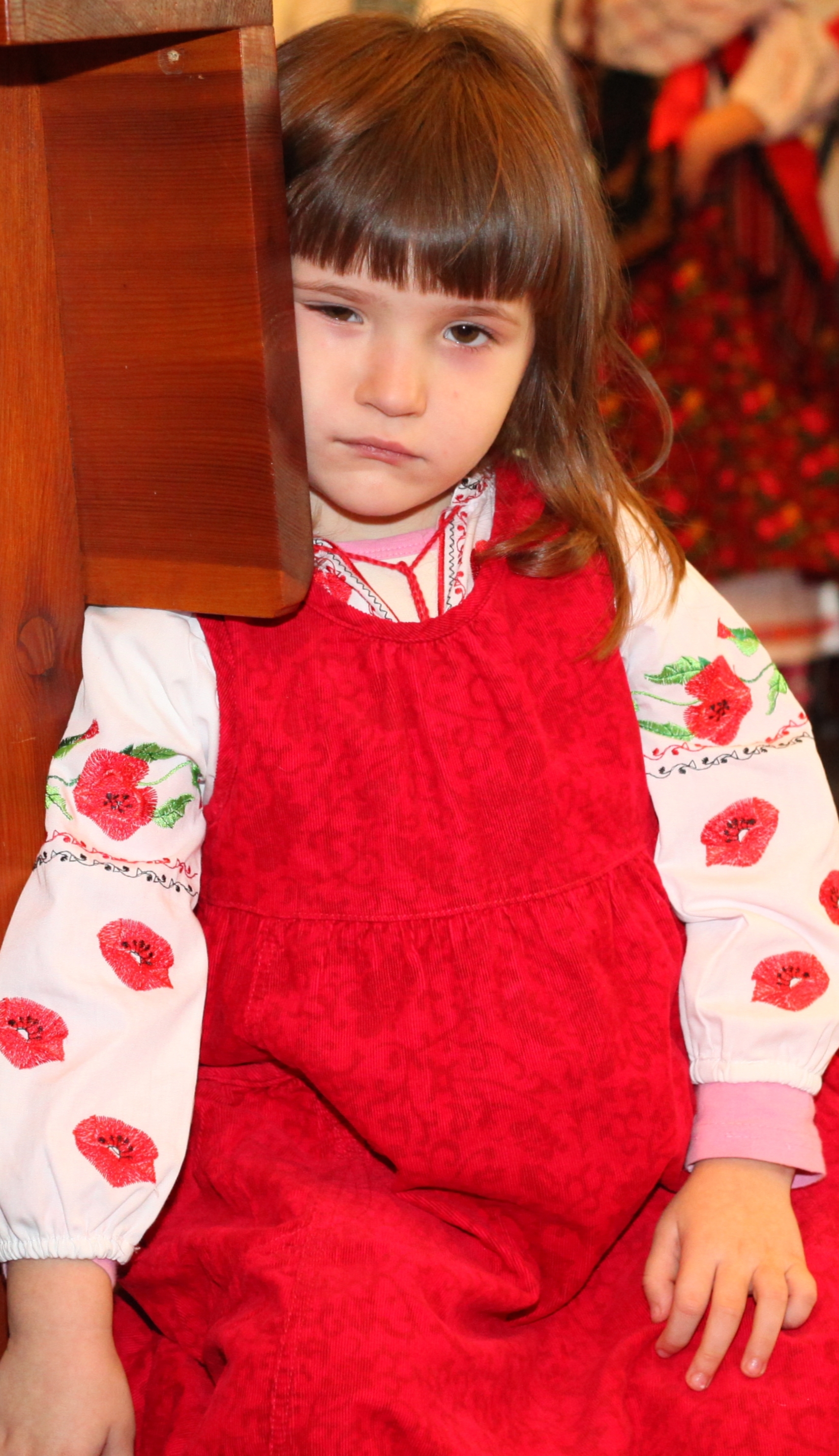 a beautiful amazing cute charming Catholic child girl in a red dress in a Church looks sad, photo 4