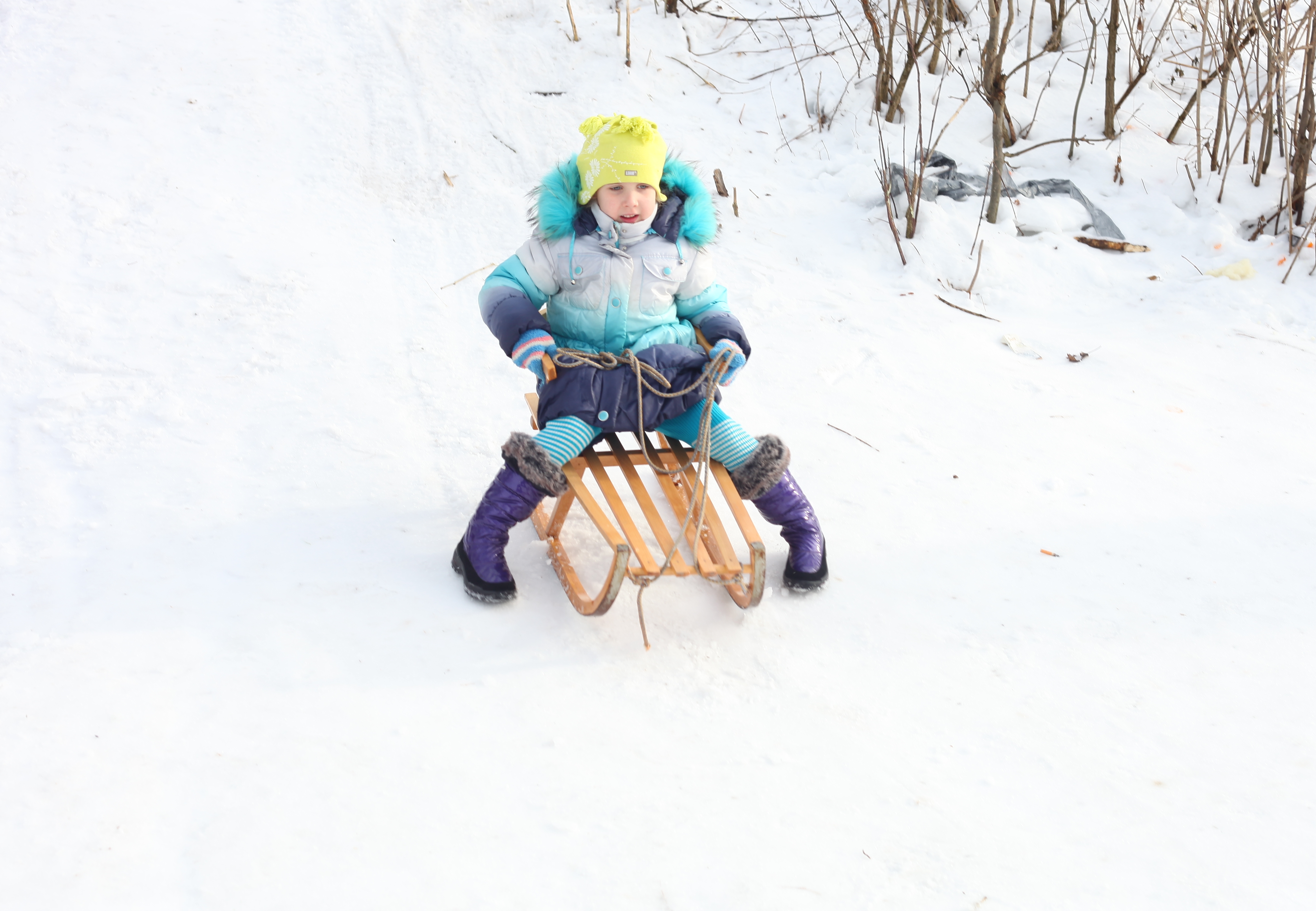 a child girl riding on a sled from a hill 