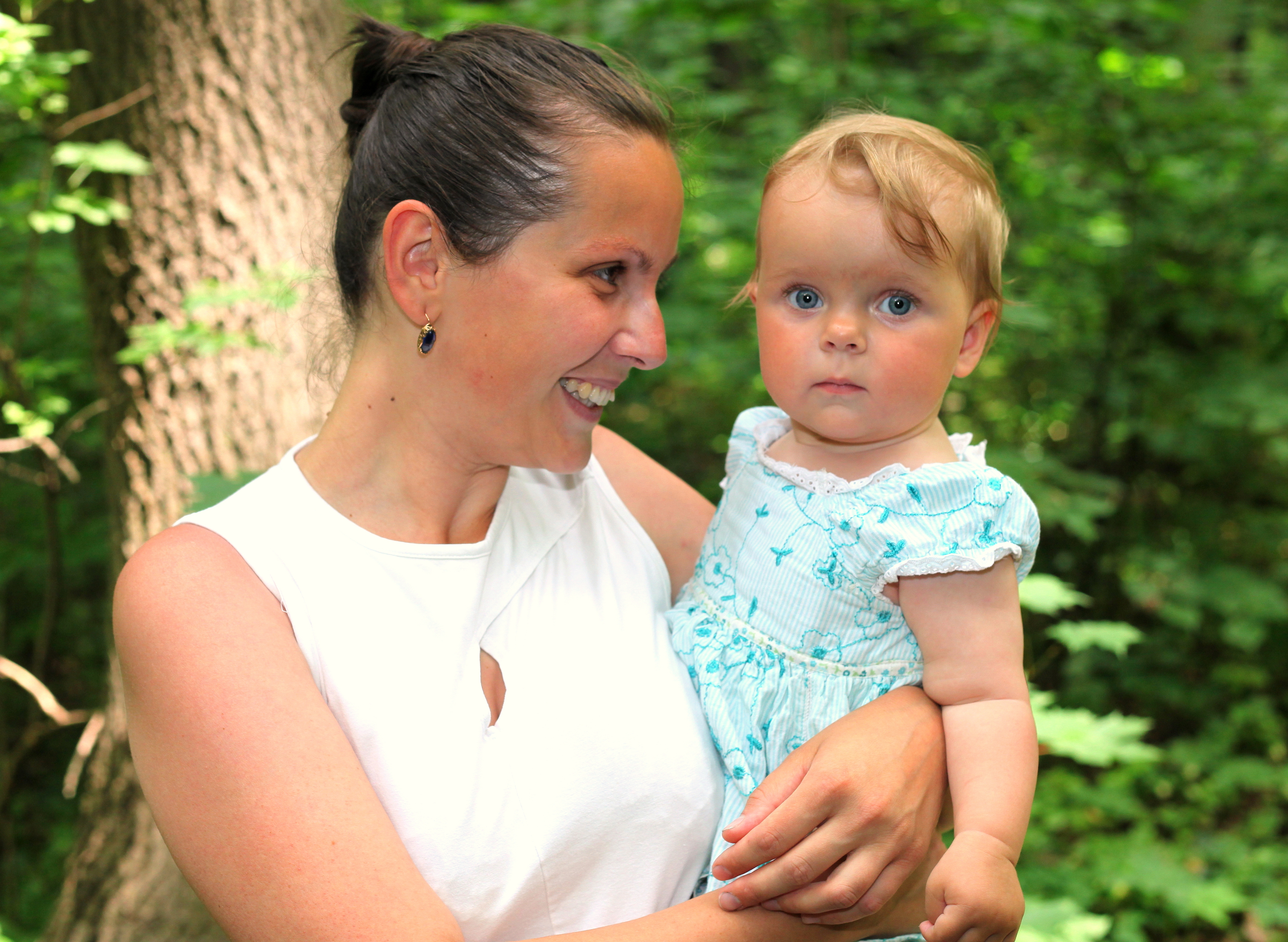 a pretty brunette Catholic mother holding her third kid in June 2013, picture 2/3