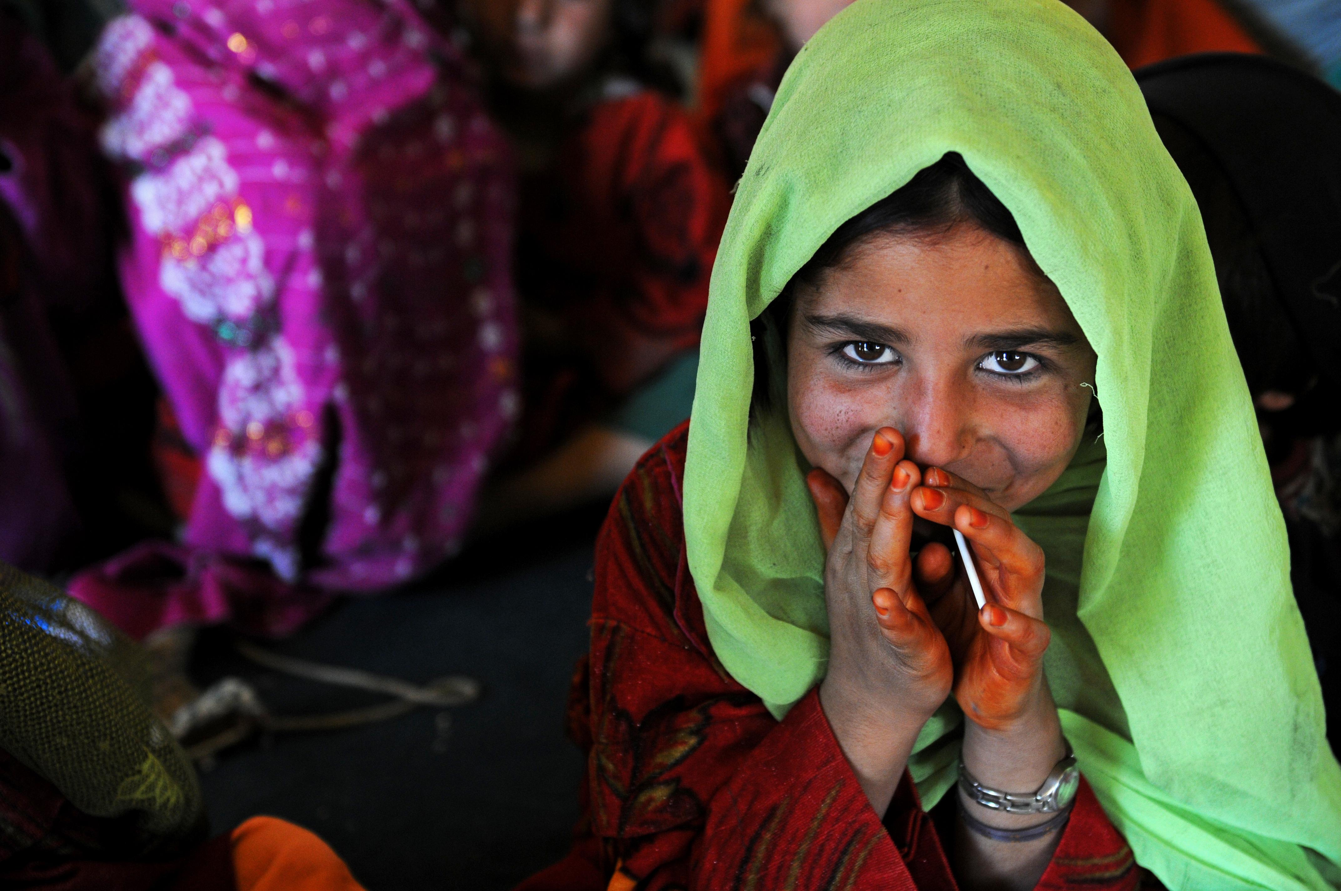 A young Afghan girl smiles shyly 