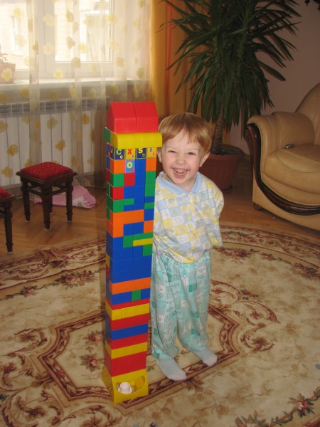 a small boy with one of his first constructed buildings