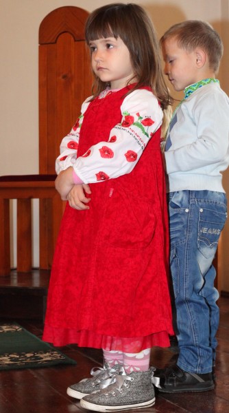 a beautiful amazing cute charming Catholic child girl in a red dress in a Church, photo 3