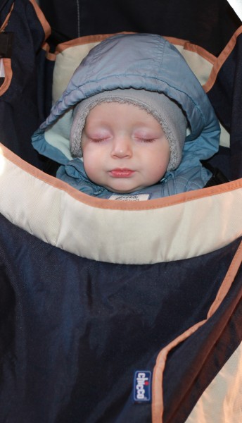 a cute Catholic baby boy sleeping in a pram