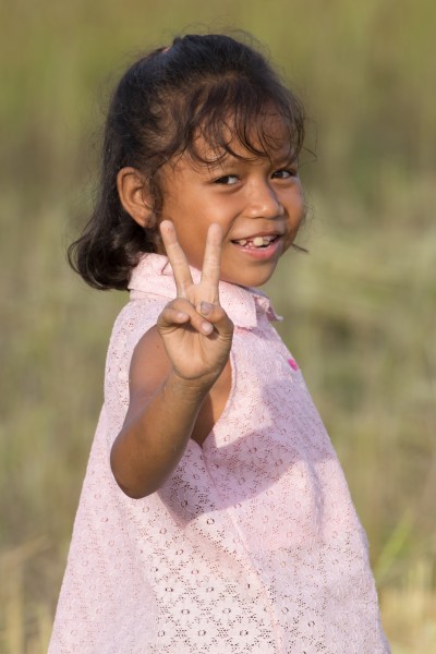 Little girl giving V-sign in the sunshine in Laos