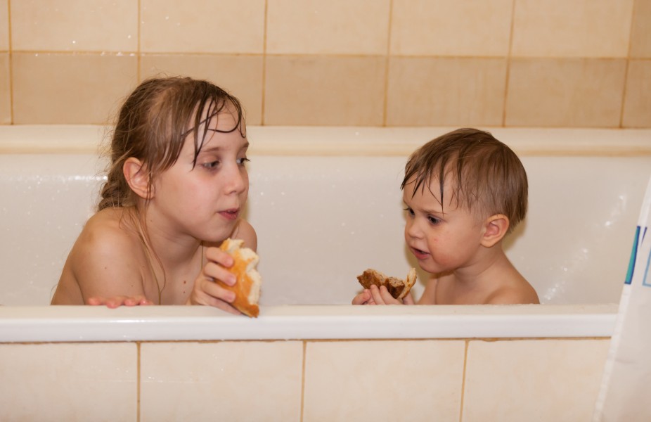 sister and brother having snacks in a bathtub in March 2016