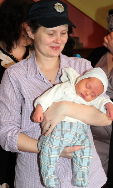 a young Catholic woman holding her third child