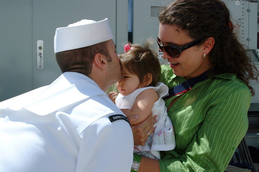US Navy 050608-N-6504N-002 Journalist 1st Class Joshua Smith kisses his baby on the pier after getting off the Military Sealift Command (MSC) hospital ship USNS Mercy (T-AH 19)