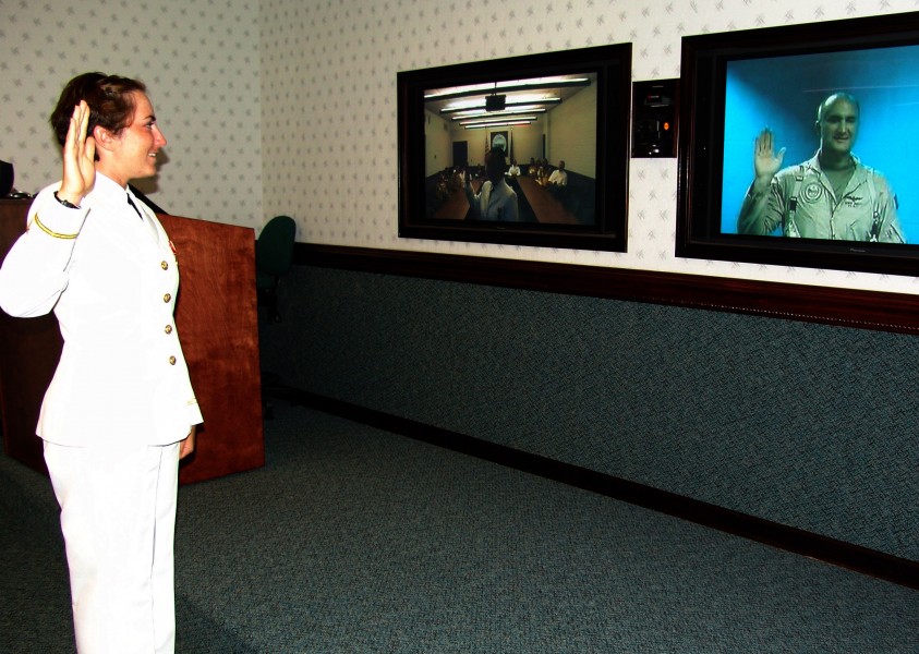US Navy 070831-N-9246G-009 Ensign Lindsey Sinnett takes the oath of commissioning from her father, Capt. Dennis Sinnett, currently serving in Iraq, via a video teleconference (VTC)