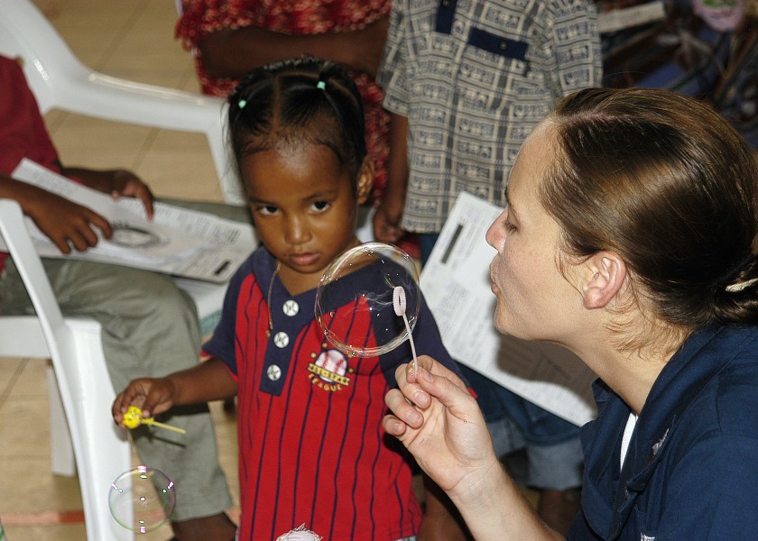 US Navy 070901-N-9195K-032 Aviation Ordnanceman 3rd Class Ashley Cameron blows soap bubbles for a local child while assisting with a medical civic action program held at Delap High School