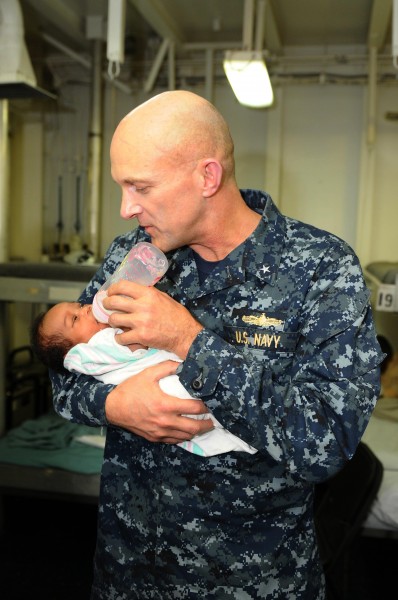 US Navy 100130-N-8936G-028 Rear Adm. David Thomas Jr., commander of Carrier Strike Group 2, feeds a Hatian infant in the medical department of the amphibious assault ship USS Nassau (LHA 4)