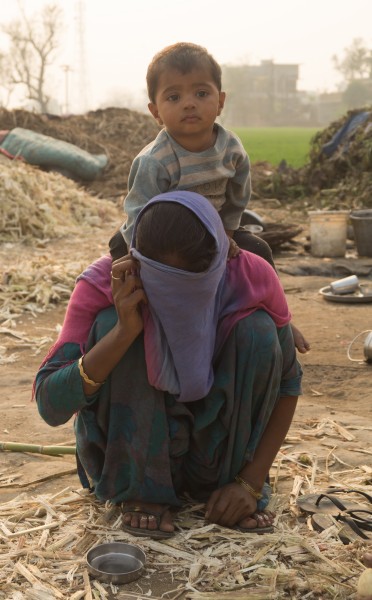 Woman covering her face with her child on her back