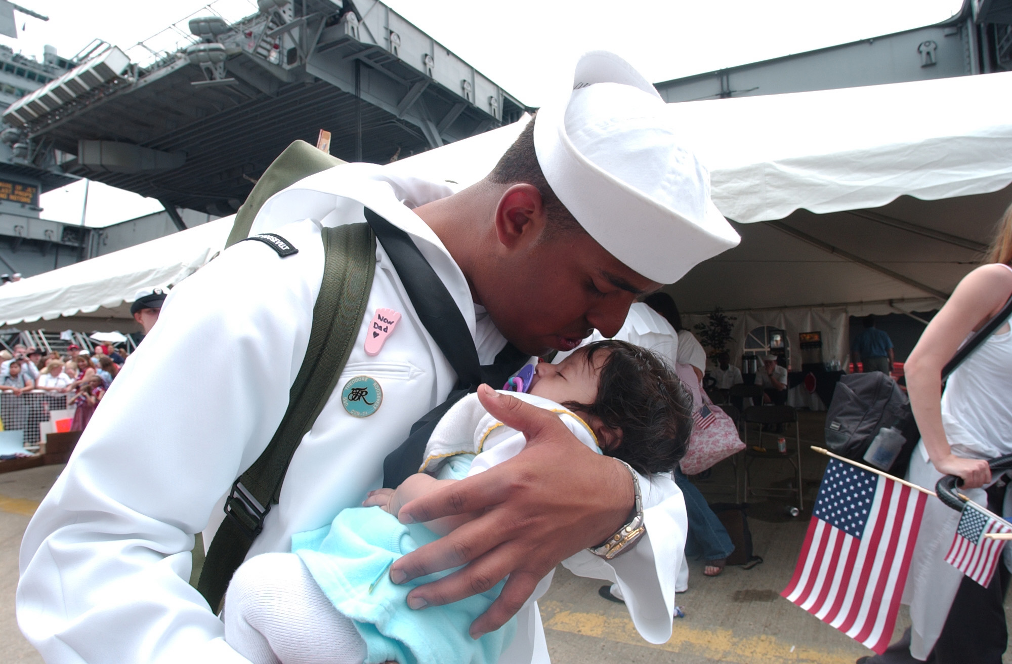 US Navy 030529-N-3642E-001 Airman Andy Nunez kisses his newborn son for the first time after returning from deployment aboard USS Theodore Roosevelt (CVN 71)
