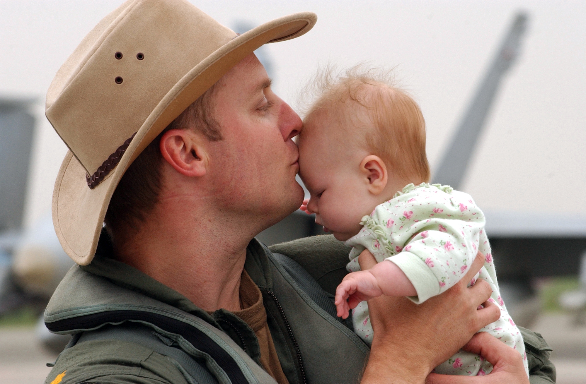 US Navy 040522-N-0435H-001 Lt. Cmdr Sean Cushing kisses his daughter after his return from a deployment