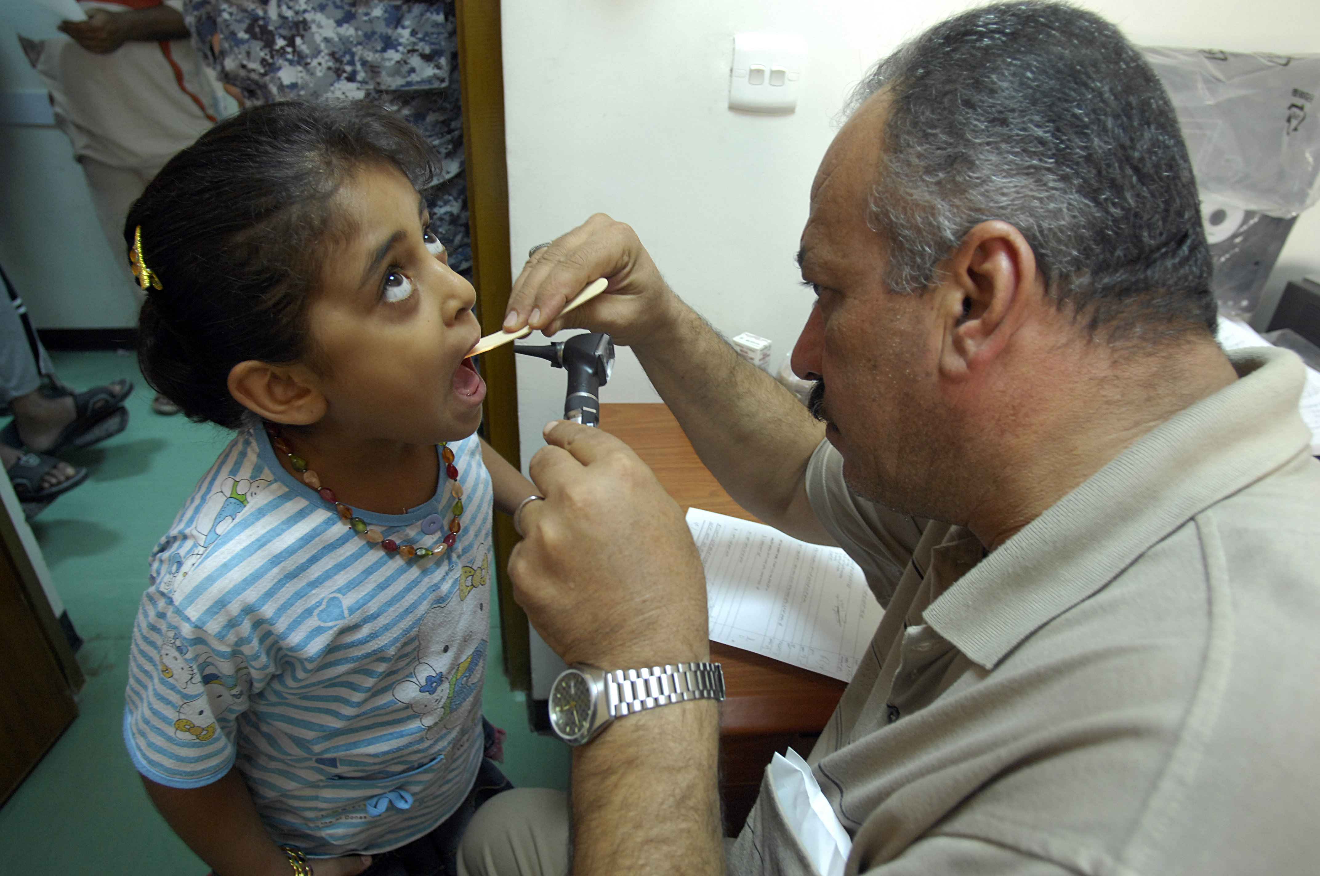 US Navy 080828-N-0292S-005 An Iraqi doctor checks a child's throat during an examination at a free health clinic during a combined medical event for local Iraqi families