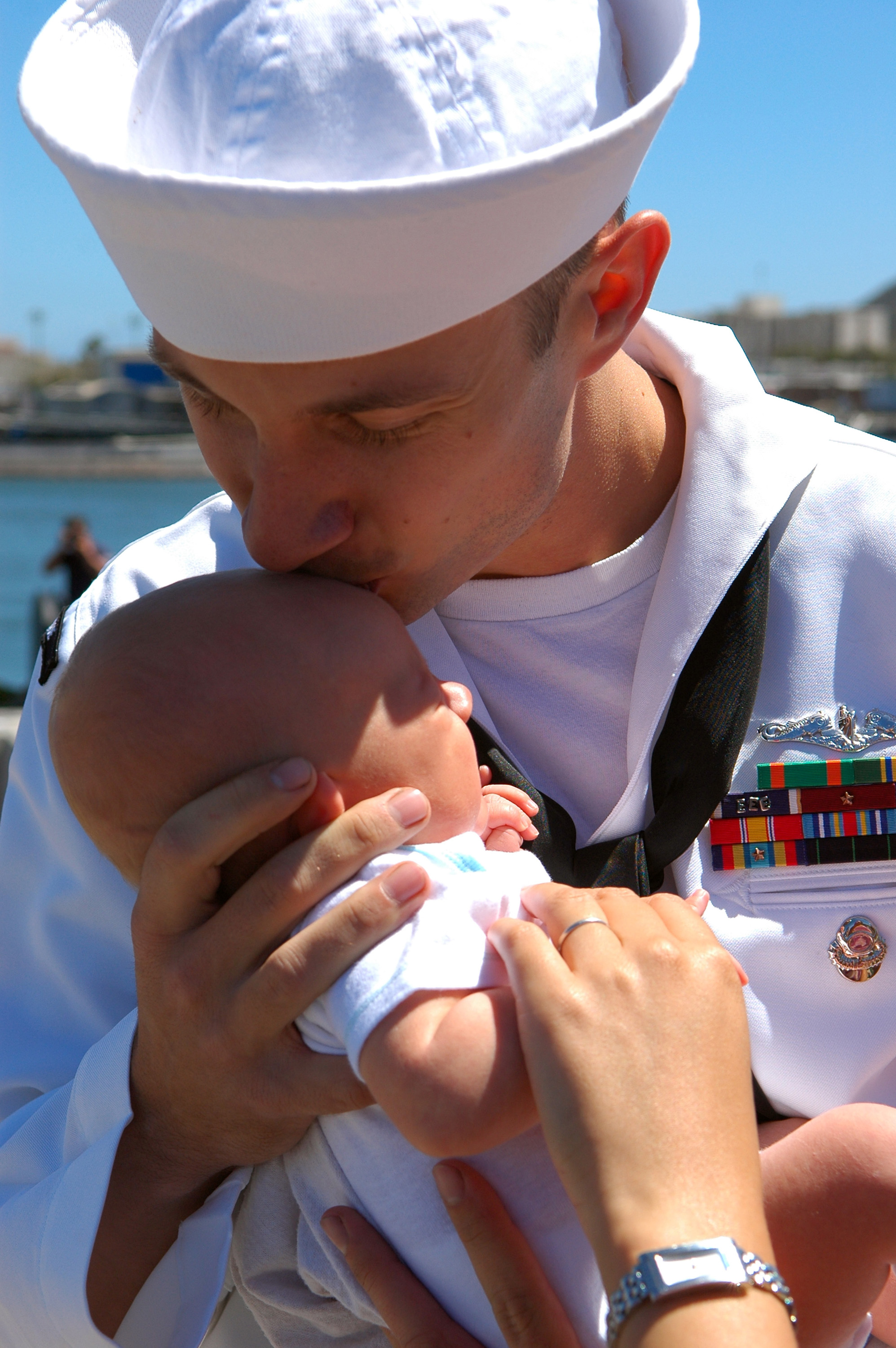 US Navy 090806-N-6031Q-001 A Sailor assigned to the Los Angeles-class attack submarine USS Albuquerque (SSN 706) kisses his baby as he arrives in San Diego