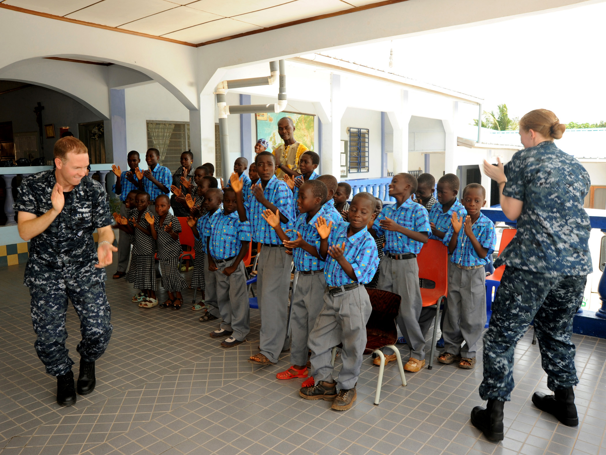 US Navy 100314-F-4109M-017 Musician 2nd Class Justin Strauss and Musician 2nd Class Allison Baine clap along with boys and girls from the Egyam Orphanage Foundation