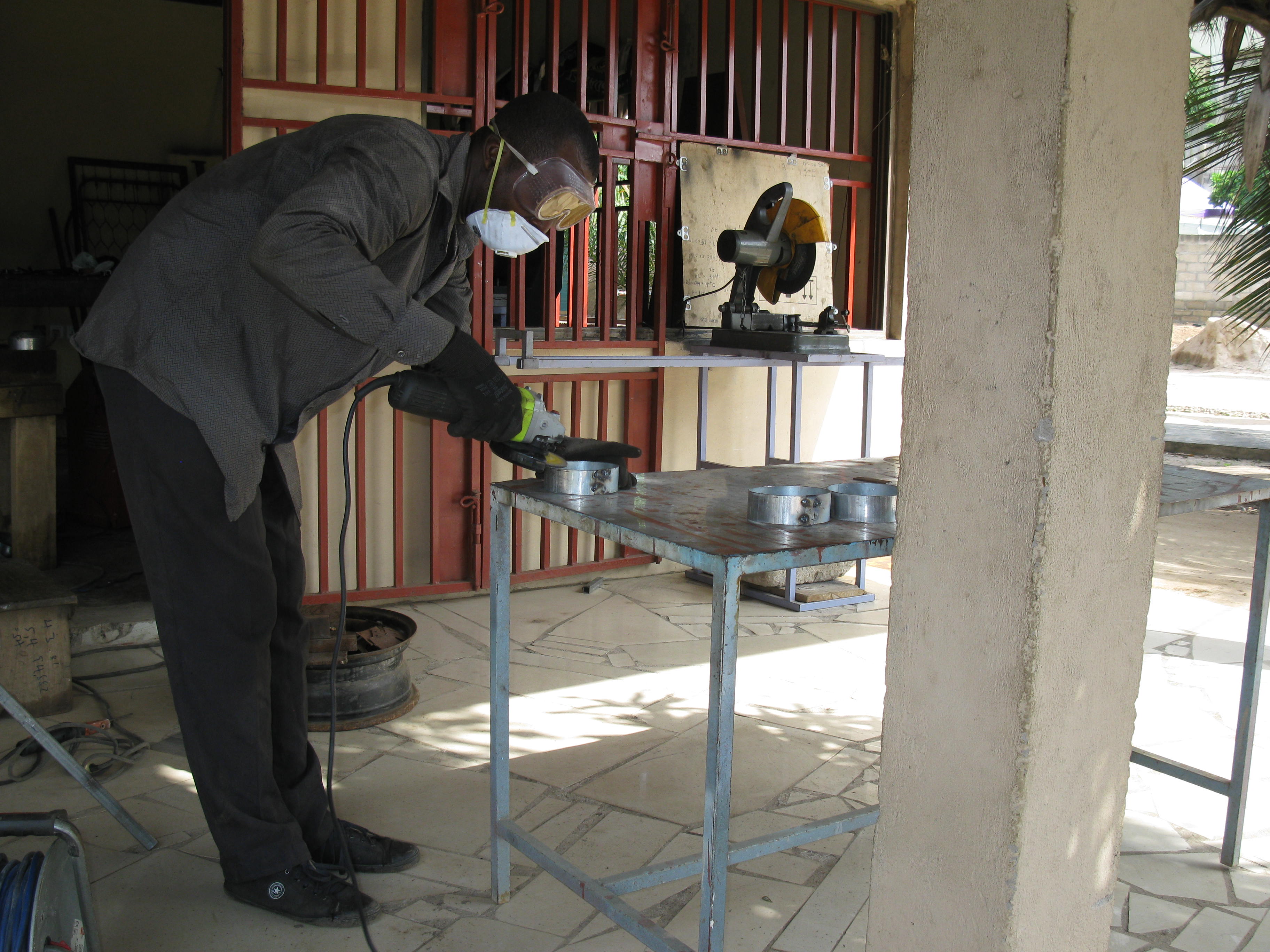 A Ghanaian Metal Fabricator using a grinding machine
