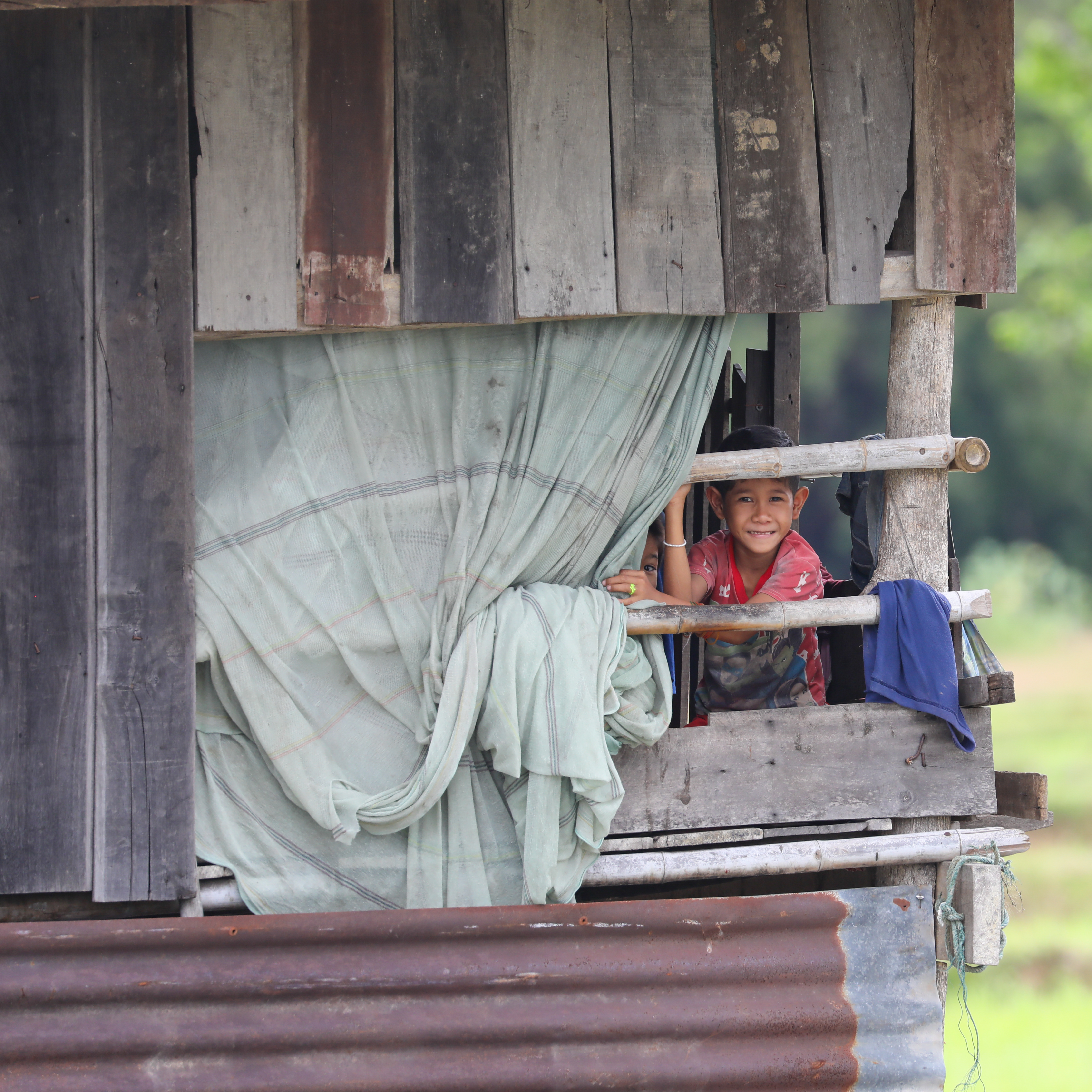 Boys at window of a wooden house
