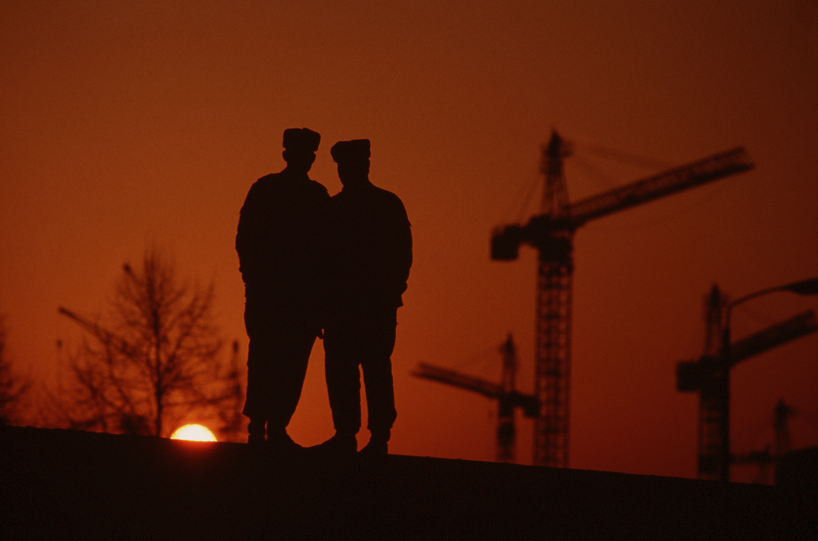 East German policemen, Berlin Wall at sunset