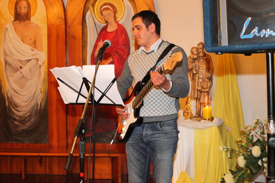 a Catholic man playing an electronic guitar in a Church