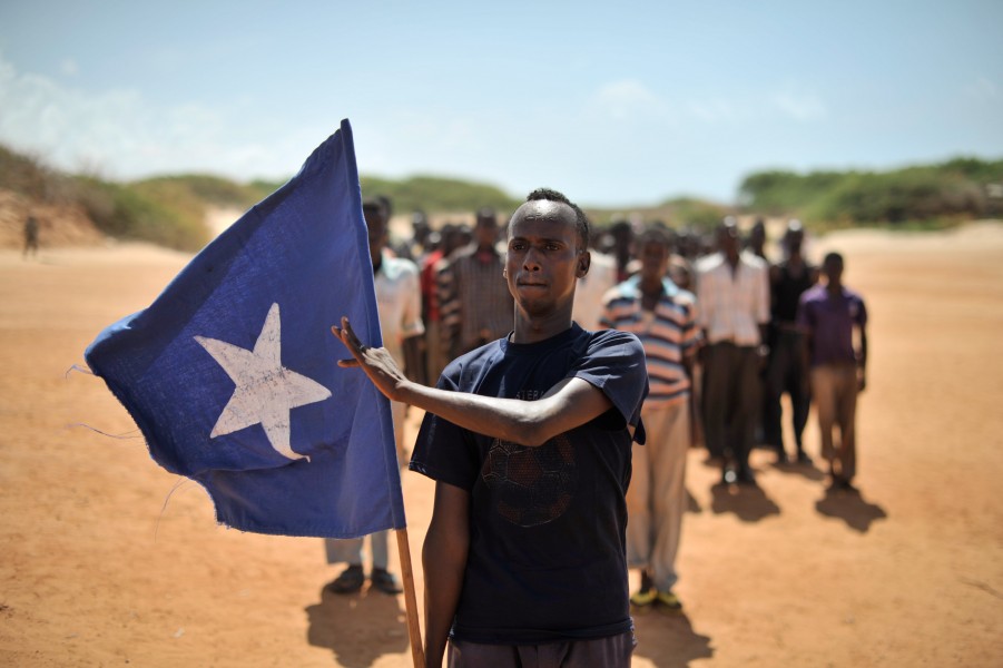 A young man carries the Somali flag while leading a group of soldiers during a demonstration by a local militia, formed in order to provide security in the town of Marka, Somalia, on April 30. AU UN (14077872251)