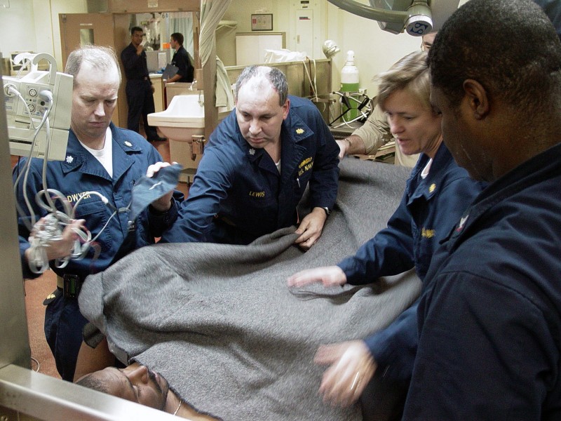 US Navy 030108-N-2338M-006 U.S. Navy nurse Cmdr. Brian Lewis covers a rescued fisherman with a wool blanket as the attending doctor