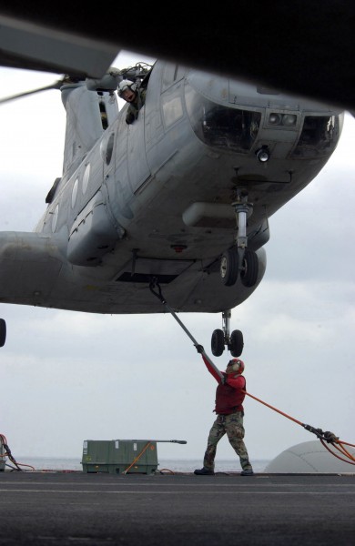 US Navy 030328-N-7265L-005 An Aviation Ordnanceman assigned to the G-1 (Flight Deck Ordnance) division attaches cargo straps to a CH-46D Sea Knight helicopter 