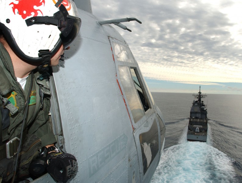 US Navy 031109-N-9769P-059 Aviation Ordnanceman 3rd Class Robert Parizo looks out the crew window of a CH-46D Sea Knight to help with the approach as the helicopter prepares to land aboard the guided missile cruiser USS Lake Ch