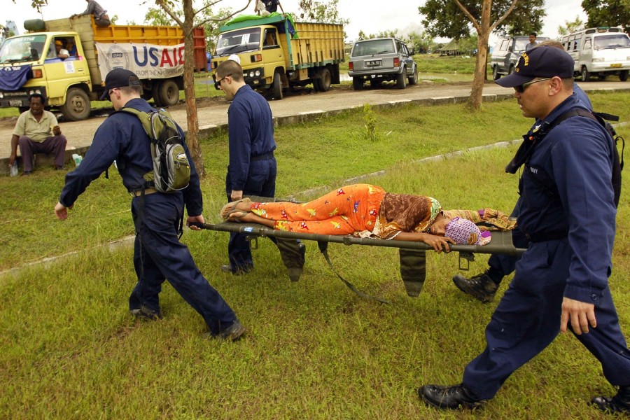 US Navy 050116-N-6074Y-161 Sailors assigned to the USS Abraham Lincoln (CVN 72) Carrier Strike Group, carry a sick Indonesian woman to a makeshift medical facility set up at the air base in Banda Aceh