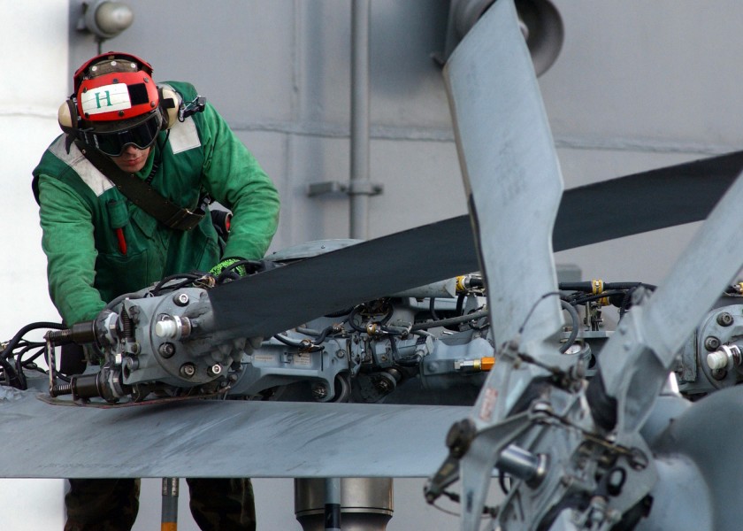US Navy 050201-N-5345W-174 Aviation Ordnanceman 3rd Class Lonnie Clingerman performs daily maintenance on the main rotors of an SH-60 Seahawk