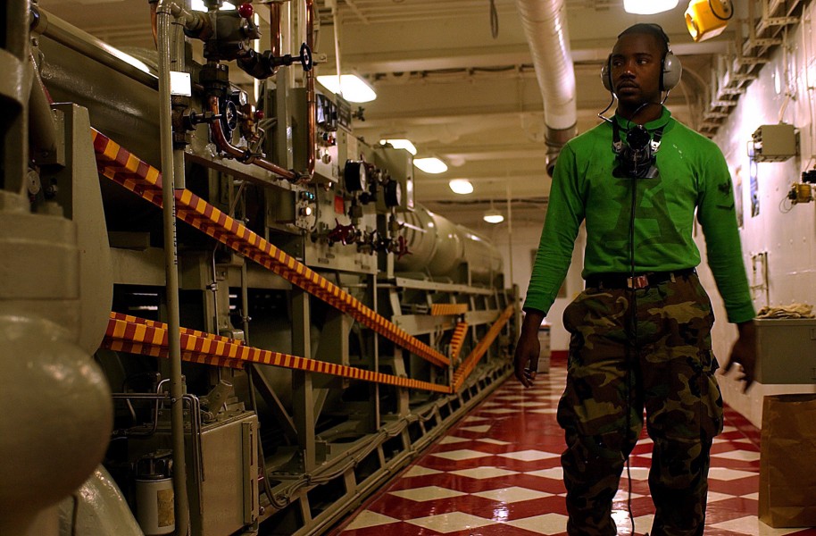 US Navy 050628-N-7130B-015 Aviation Boatswain's Mate 3rd Class Ahrmon Rudolph conducts a visual inspection of his equipment while standing the Number One Arresting Gear Engine Watch