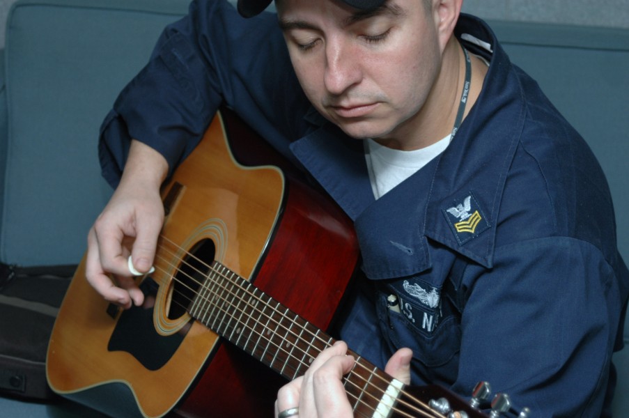 US Navy 051204-N-0000L-001 Information Systems Technician 1st Class Keith Grommes spends some time relaxing, while playing his guitar aboard the guided missile destroyer USS Donald Cook (DDG 75)