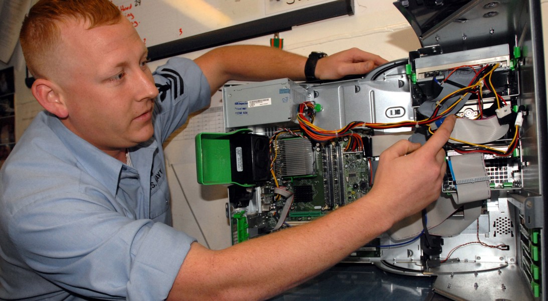 US Navy 060322-N-0555B-034 Information Systems Technician 1st Class Chris Hedger inspects the internal components of a computer during Information Security (INFOSEC) training